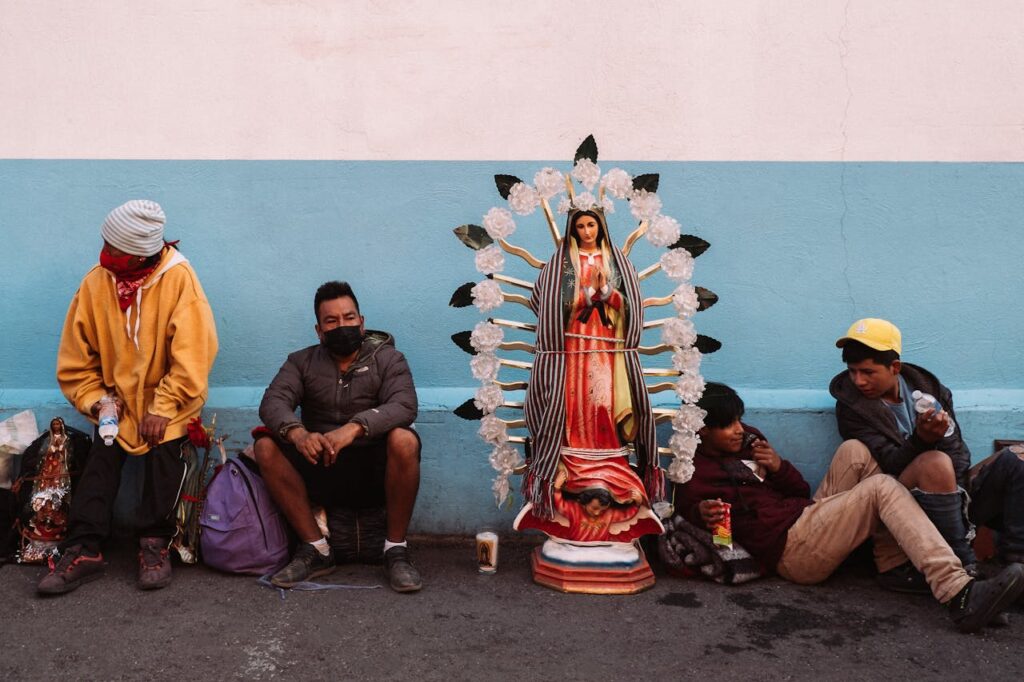 People sitting by a statue of Our Lady of Guadalupe in Ciudad de México, showcasing cultural and religious themes.