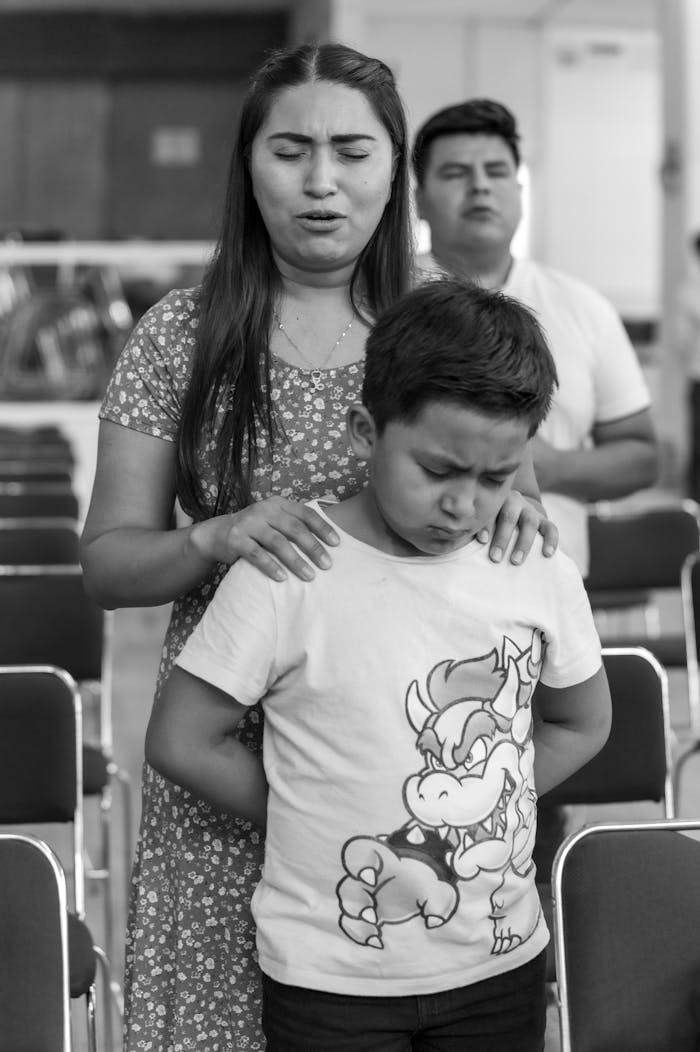 A mother prays over her son at a parish gathering (black-and-white photo)